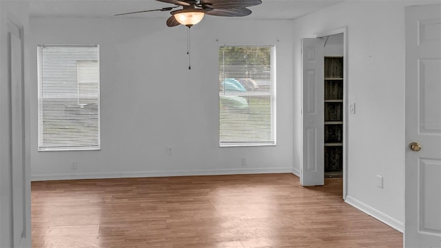 spare room with a ceiling fan, light wood-type flooring, and baseboards