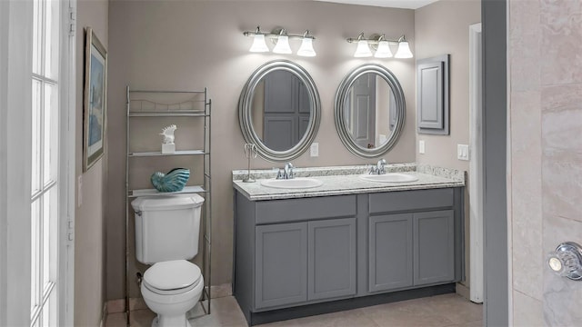 bathroom featuring tile patterned flooring, a sink, toilet, and double vanity