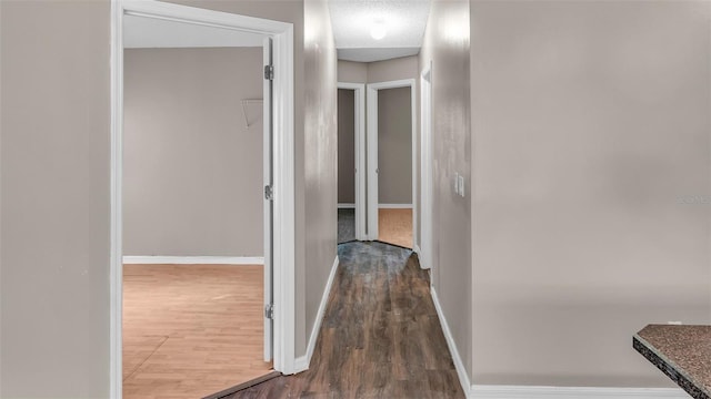 hallway with dark wood-style flooring and baseboards