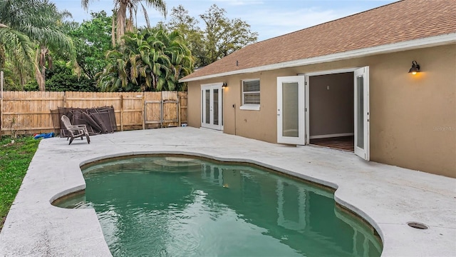 view of swimming pool featuring french doors, a patio area, a fenced backyard, and a fenced in pool