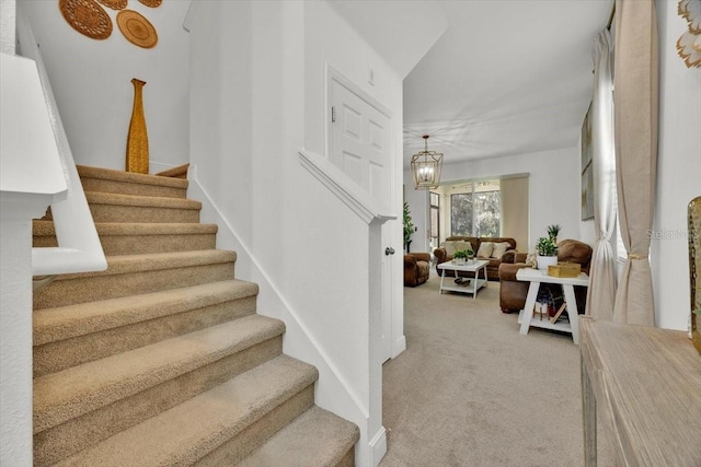 stairway featuring a notable chandelier and carpet