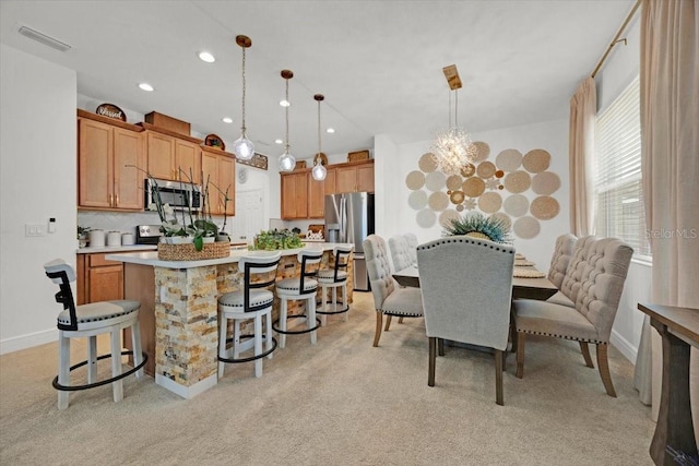 kitchen featuring backsplash, pendant lighting, a kitchen island, stainless steel appliances, and light colored carpet