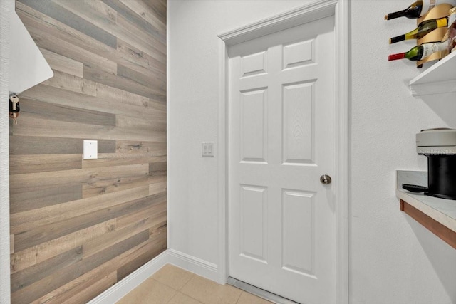 interior space with light tile patterned floors and wooden walls