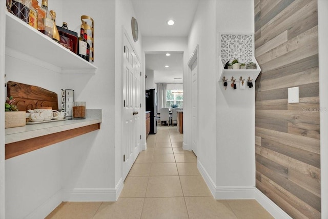 hall with light tile patterned flooring and wooden walls