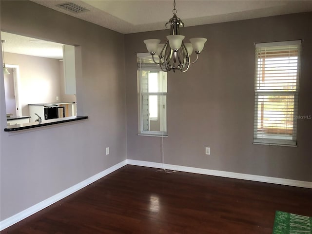 unfurnished dining area featuring dark wood-type flooring and a chandelier