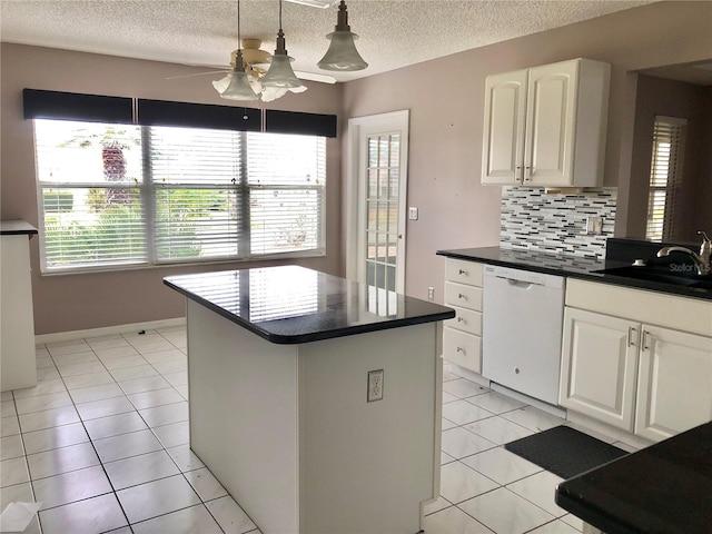 kitchen featuring white dishwasher, sink, light tile patterned floors, and white cabinets