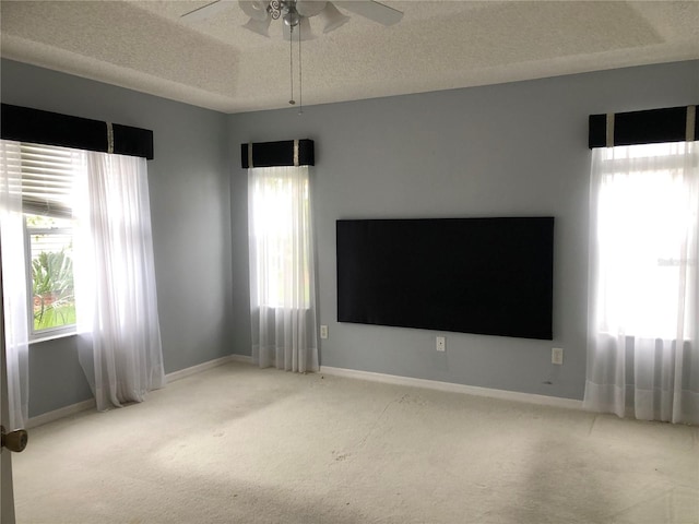 carpeted empty room with ceiling fan and a textured ceiling