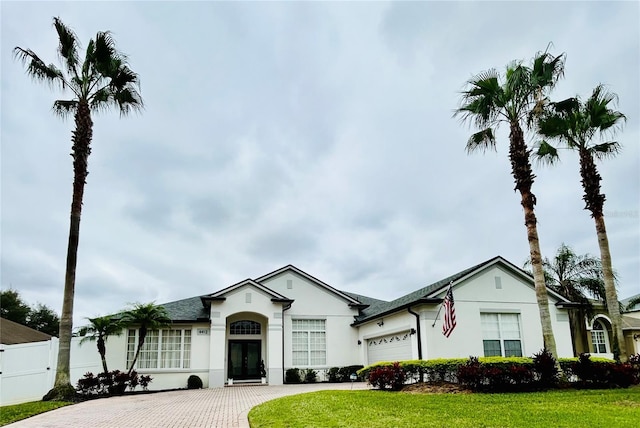 view of front facade with driveway, fence, an attached garage, and stucco siding