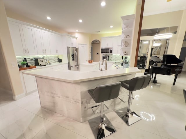 kitchen with a kitchen island with sink, stainless steel appliances, white cabinets, light countertops, and open shelves