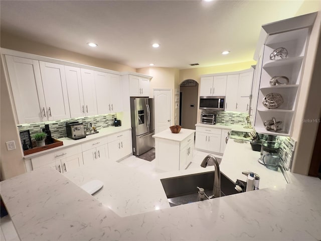 kitchen with appliances with stainless steel finishes, a center island, white cabinetry, and open shelves