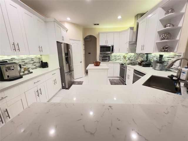 kitchen with light stone counters, a sink, visible vents, appliances with stainless steel finishes, and open shelves