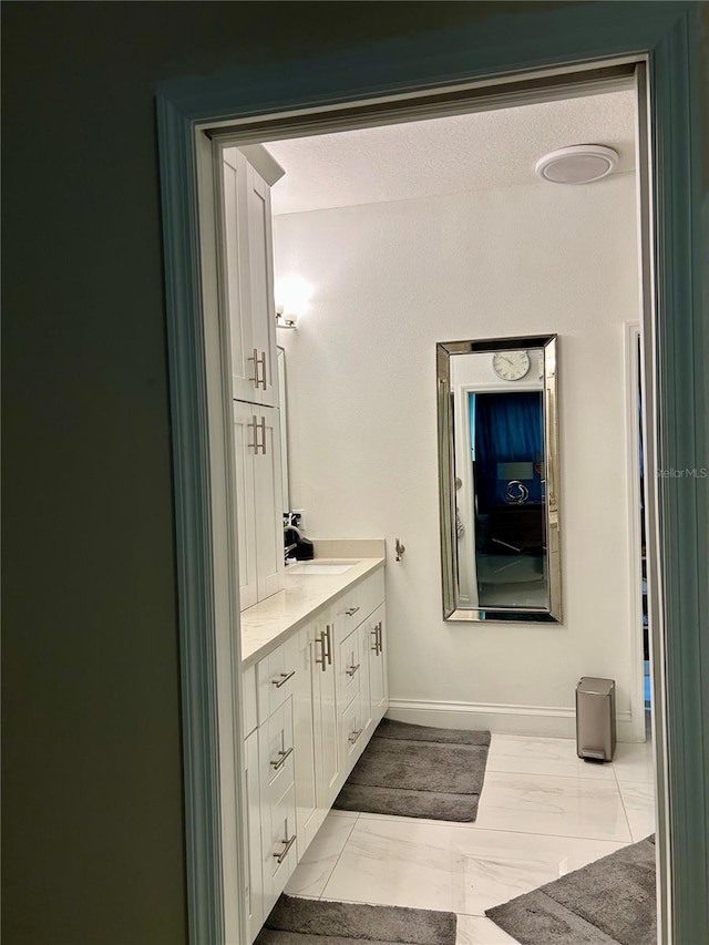 bathroom featuring marble finish floor, vanity, and baseboards