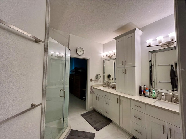 full bathroom with a sink, a shower stall, a textured ceiling, and double vanity