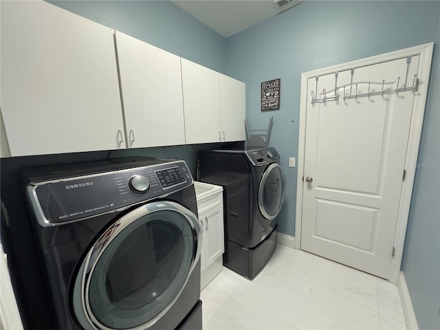 laundry area featuring cabinet space, washing machine and dryer, marble finish floor, and baseboards