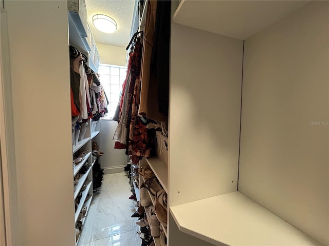 walk in closet featuring marble finish floor