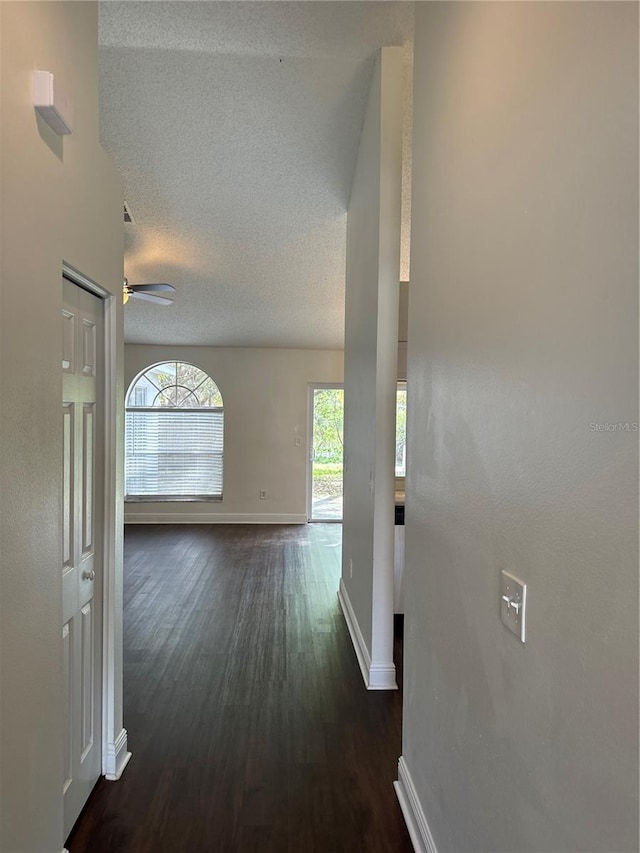 hall featuring a textured ceiling and dark wood-type flooring