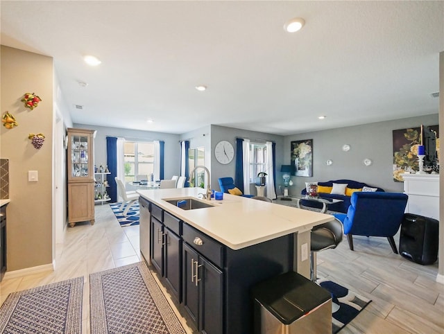 kitchen with a kitchen island with sink, sink, and a kitchen bar