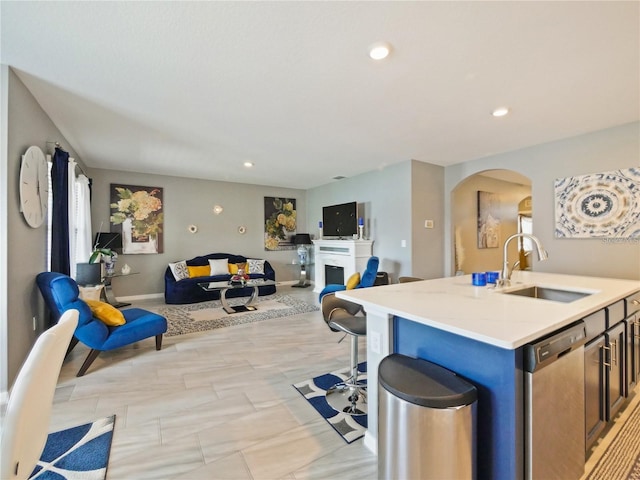 kitchen featuring dishwasher, light stone countertops, sink, and a kitchen island with sink