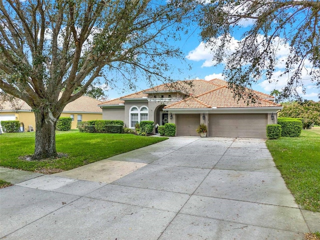 view of front of property featuring a garage, a tiled roof, driveway, stucco siding, and a front yard