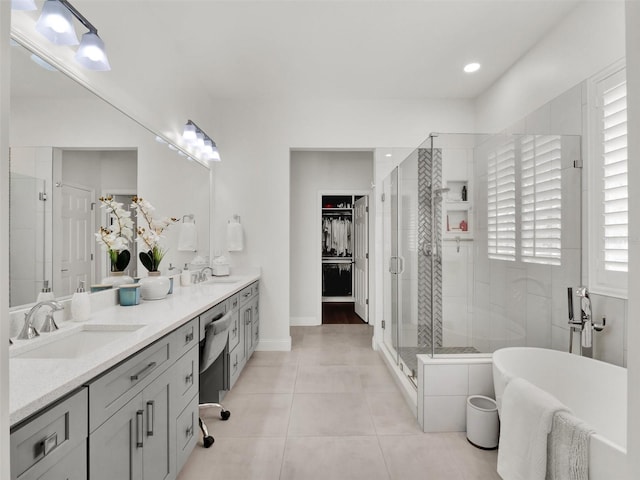 full bathroom with double vanity, tile patterned flooring, a sink, and a walk in closet