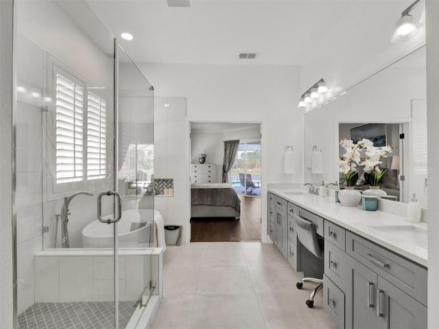 full bath featuring ensuite bathroom, a freestanding tub, tile patterned flooring, a sink, and visible vents