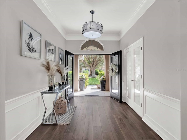 entrance foyer featuring dark wood-style floors, ornamental molding, and a wainscoted wall