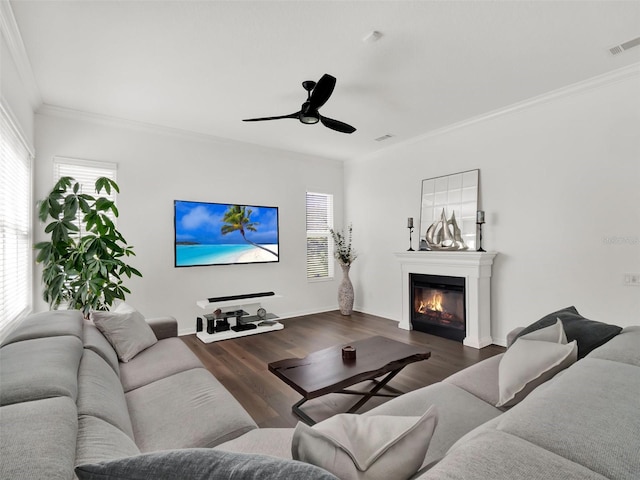 living area featuring dark wood-type flooring, a glass covered fireplace, visible vents, and a healthy amount of sunlight