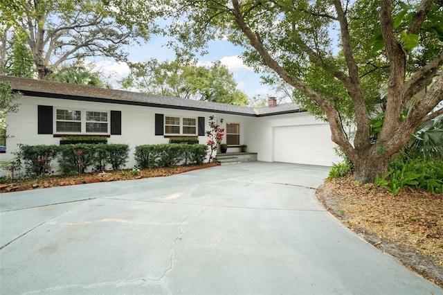 ranch-style home with a garage, concrete driveway, and a chimney