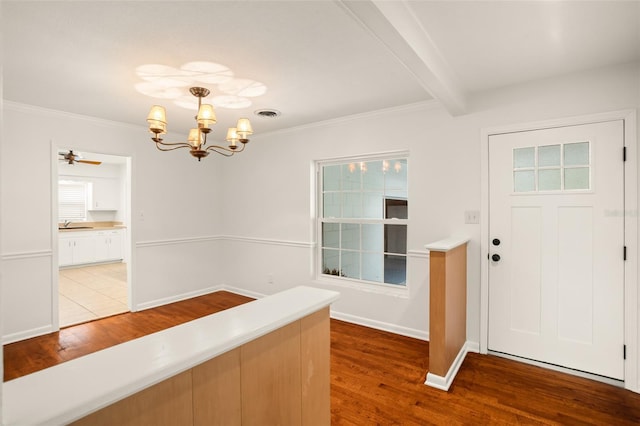 entryway with beam ceiling, a healthy amount of sunlight, an inviting chandelier, and wood finished floors