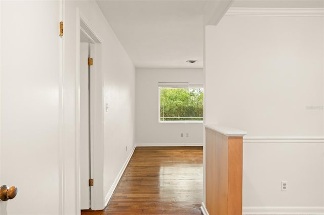 corridor with baseboards, wood finished floors, and ornamental molding