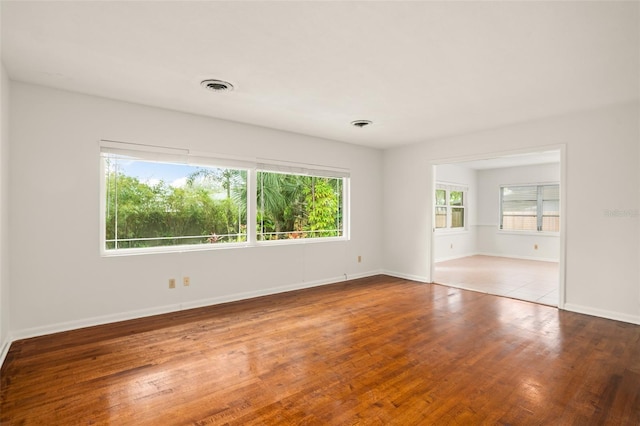 spare room featuring visible vents, baseboards, and hardwood / wood-style flooring