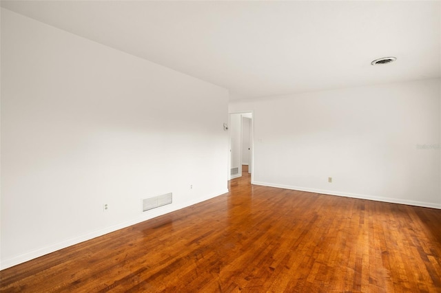 empty room featuring visible vents, baseboards, and wood finished floors