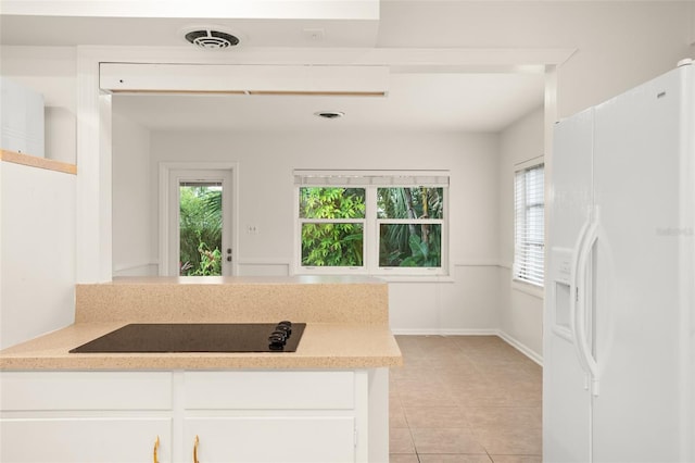 kitchen with visible vents, light countertops, white refrigerator with ice dispenser, white cabinets, and black electric cooktop