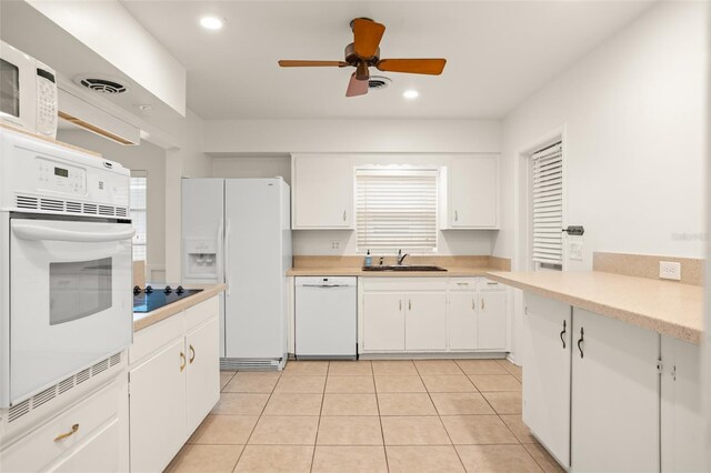 kitchen with white cabinets, white appliances, light countertops, and a sink