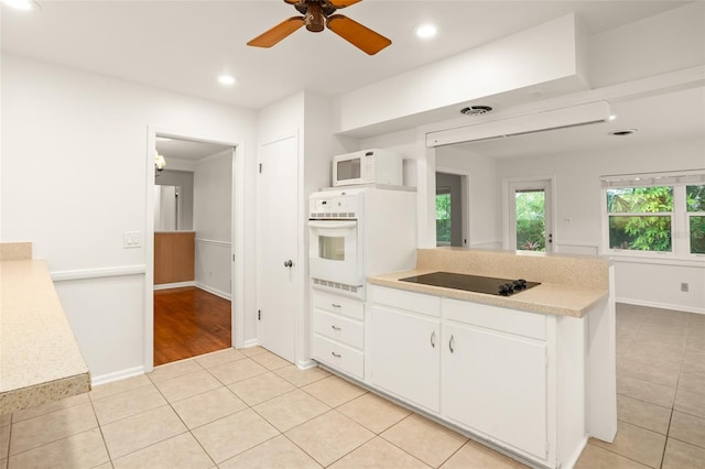 kitchen featuring white appliances, light tile patterned floors, a peninsula, light countertops, and white cabinets