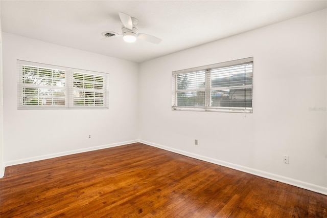 empty room with wood finished floors, a ceiling fan, and baseboards