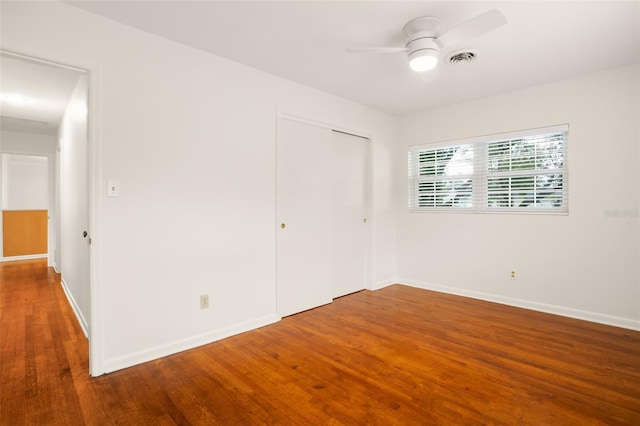 unfurnished bedroom featuring a ceiling fan, wood finished floors, visible vents, baseboards, and a closet