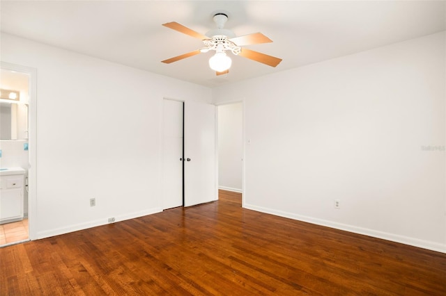 unfurnished bedroom with connected bathroom, a ceiling fan, baseboards, and wood finished floors