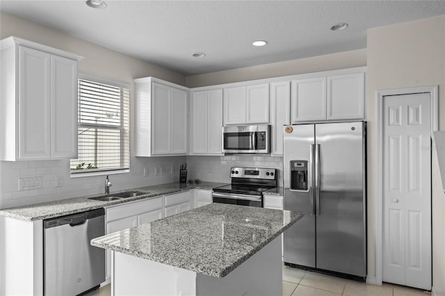 kitchen featuring white cabinetry, light stone counters, a kitchen island, and appliances with stainless steel finishes