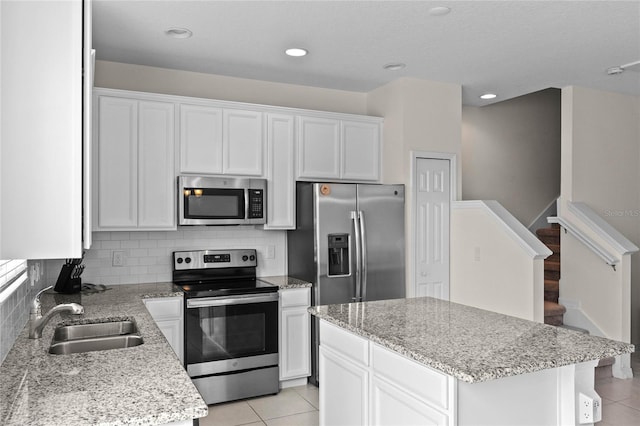 kitchen with sink, white cabinetry, light tile patterned floors, a kitchen island, and stainless steel appliances