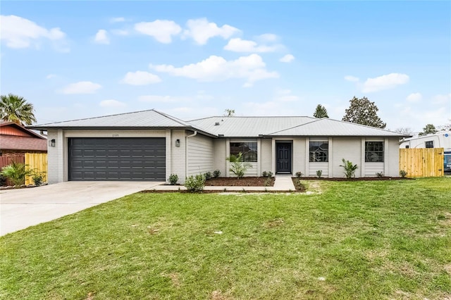 view of front of house with a garage, concrete driveway, metal roof, and a front yard