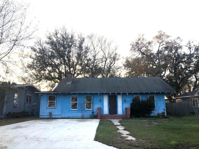 ranch-style house with fence, a chimney, and a front lawn