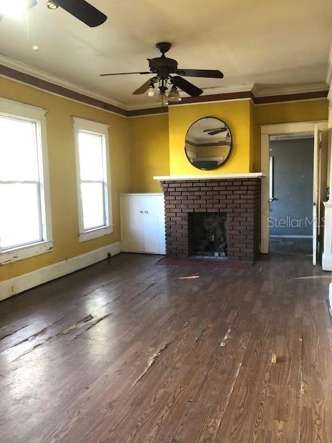 unfurnished living room with a fireplace, baseboards, dark wood-type flooring, and crown molding