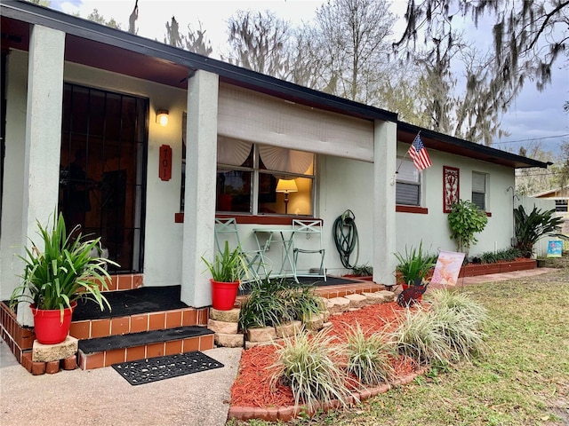 property entrance featuring covered porch and stucco siding