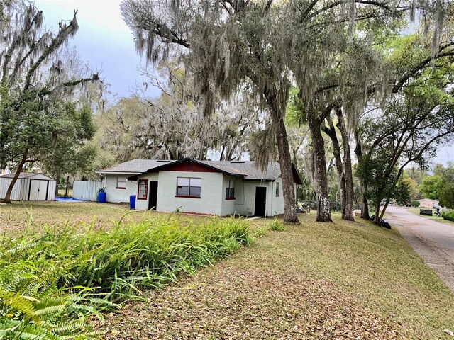 view of front of property with a storage unit, an outbuilding, stucco siding, and fence