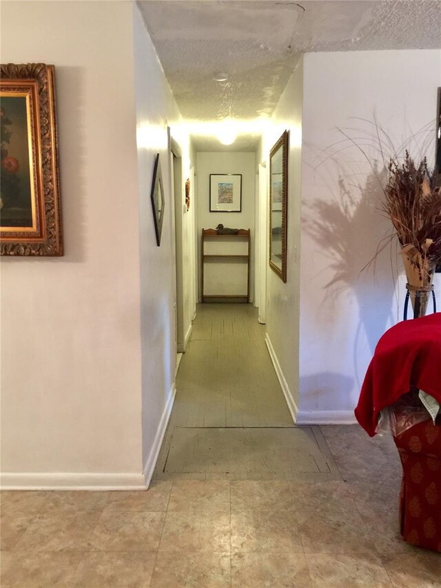 hallway featuring baseboards and a textured ceiling