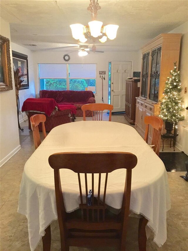dining room featuring baseboards and ceiling fan with notable chandelier