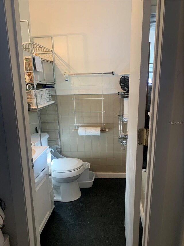 full bath with tile walls, vanity, a shower stall, and toilet