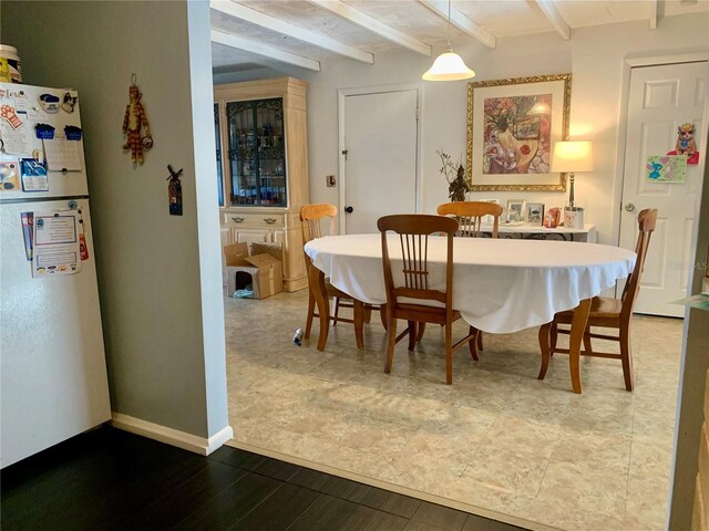 dining room with baseboards and beamed ceiling