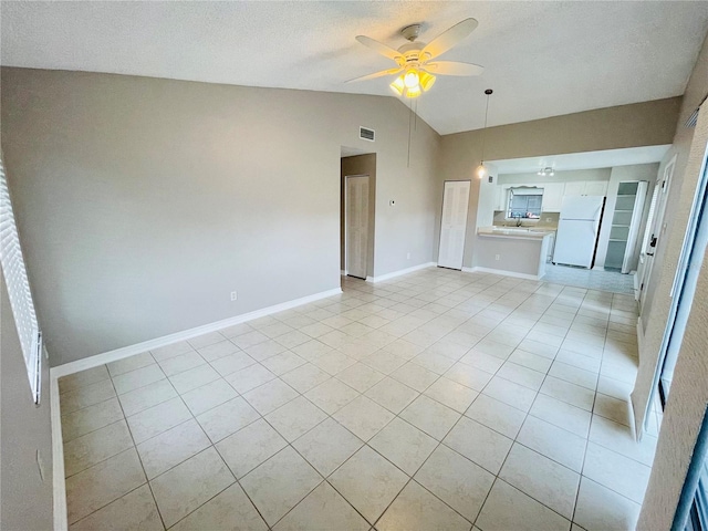 unfurnished living room with ceiling fan, vaulted ceiling, a textured ceiling, and light tile patterned floors